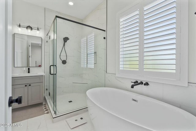 full bathroom featuring marble finish flooring, vanity, a marble finish shower, a freestanding bath, and recessed lighting