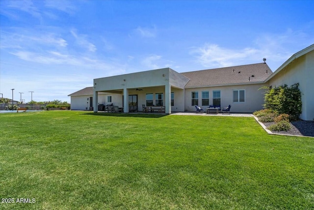 back of house featuring a ceiling fan, a patio area, a yard, and stucco siding