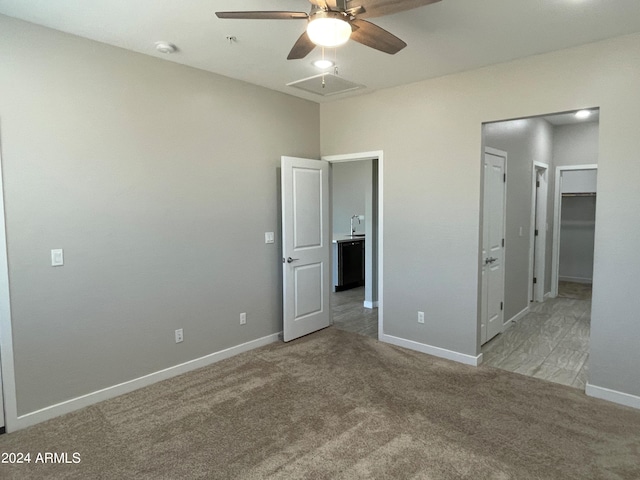 unfurnished bedroom with a spacious closet, light carpet, and ceiling fan