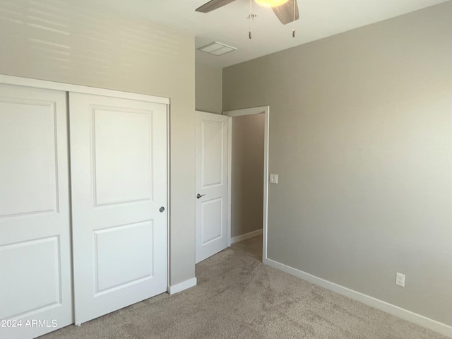 unfurnished bedroom featuring light carpet, a closet, and ceiling fan