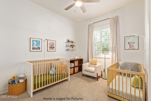 bedroom with a crib, carpet, and ceiling fan