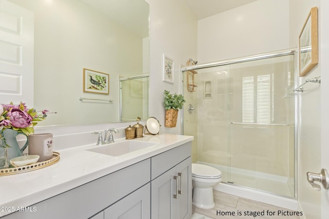 bathroom featuring toilet, a shower with shower door, tile patterned floors, and vanity