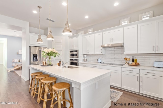 kitchen featuring white cabinetry, a center island with sink, and stainless steel appliances