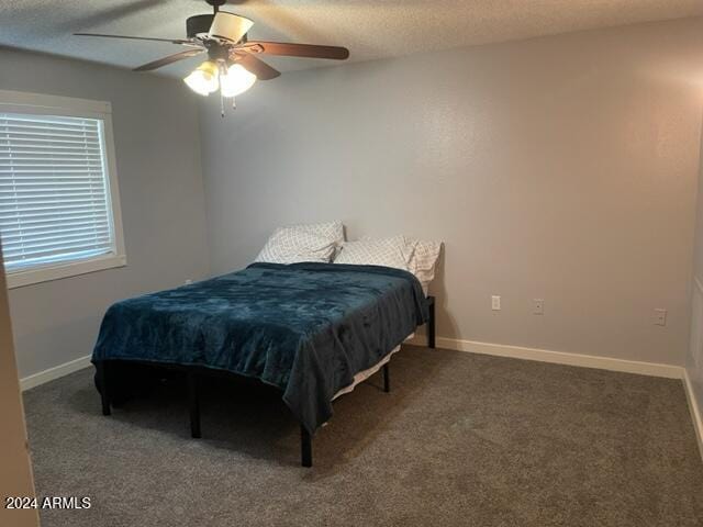 carpeted bedroom featuring ceiling fan and a textured ceiling