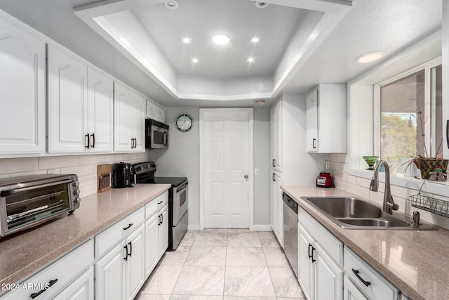 kitchen featuring white cabinets, a raised ceiling, sink, tasteful backsplash, and stainless steel appliances