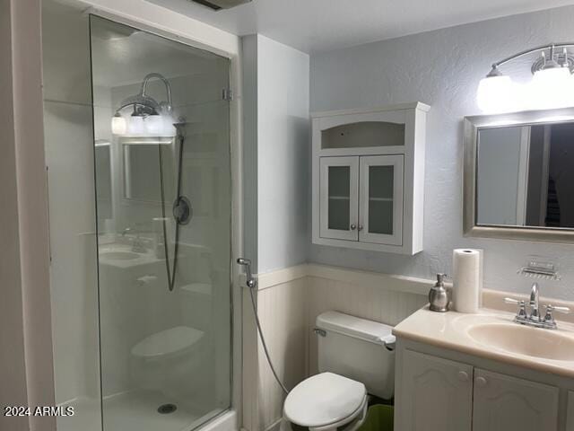 bathroom featuring vanity, toilet, and a shower with door