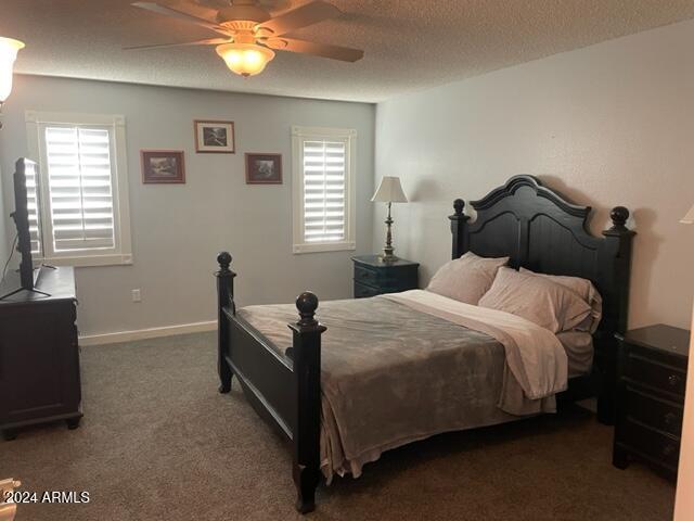 carpeted bedroom featuring ceiling fan, a textured ceiling, and multiple windows