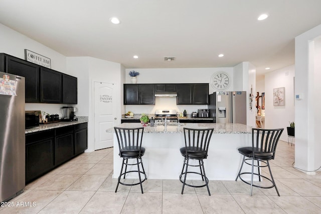30777 W Whitton Ave, Buckeye, AZ 85396 - kitchen featuring appliances with stainless steel finishes, dark cabinetry, under cabinet range hood, light stone counters, and recessed lighting