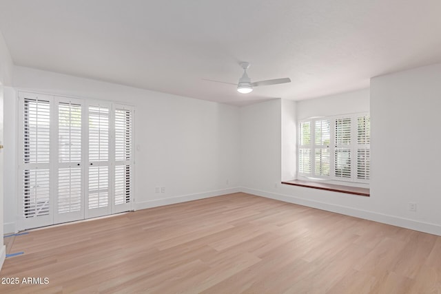 empty room featuring light wood-style flooring, a ceiling fan, and baseboards