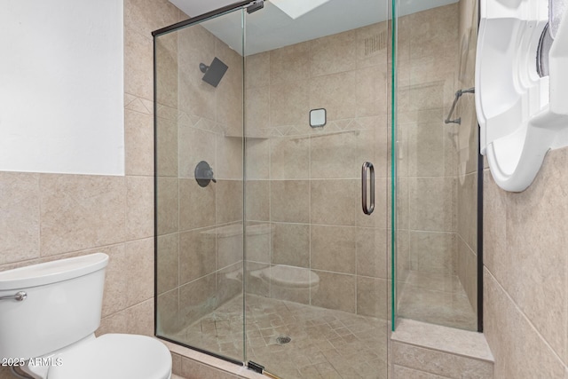 full bath with a shower stall, toilet, and tile walls