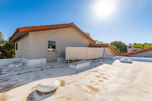 view of side of property with a tiled roof and stucco siding