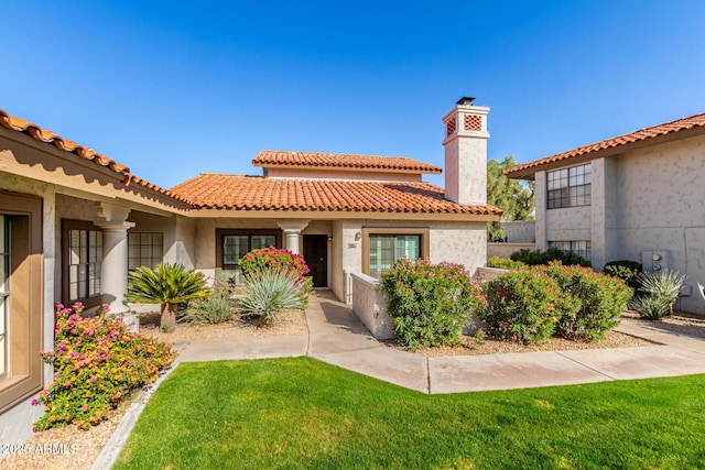 view of front of home with a chimney, stucco siding, a tile roof, and a front yard