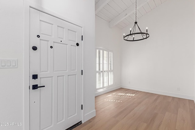 foyer entrance with beamed ceiling, a notable chandelier, wooden ceiling, light wood finished floors, and baseboards