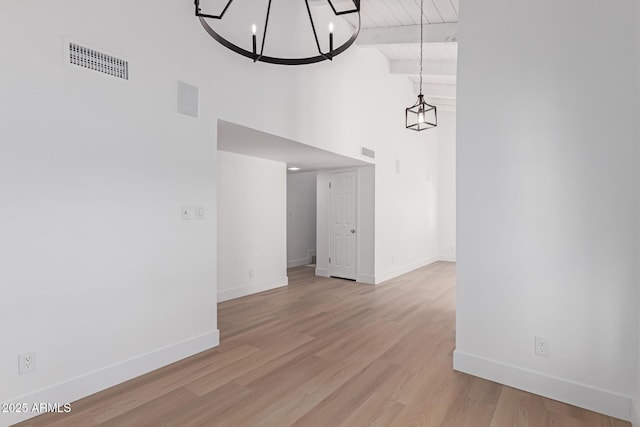 interior space featuring visible vents, beam ceiling, wood finished floors, and a chandelier