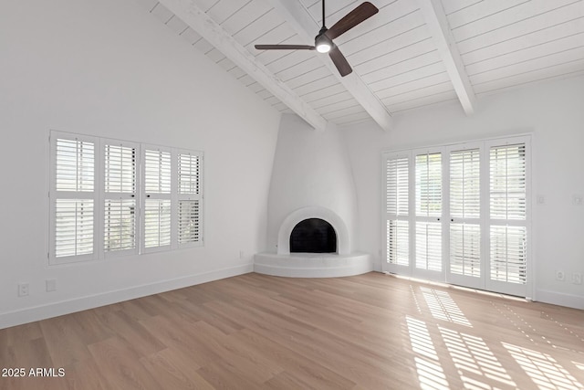 unfurnished living room featuring beamed ceiling, light wood-type flooring, a large fireplace, and baseboards