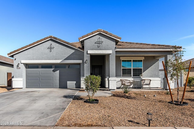 view of front of property with a porch, a garage, a tile roof, driveway, and stucco siding