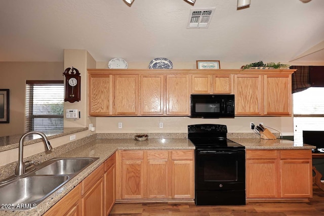 kitchen with black appliances, light wood-type flooring, and sink