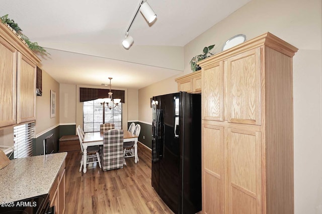 kitchen with light brown cabinets, black appliances, a chandelier, and hardwood / wood-style floors