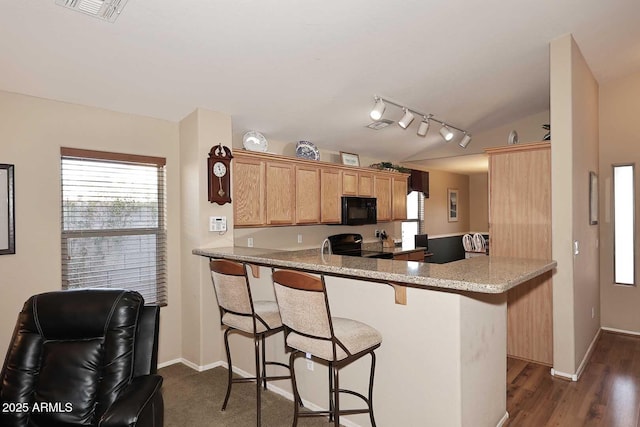 kitchen featuring light stone counters, kitchen peninsula, dark hardwood / wood-style floors, electric range, and a breakfast bar area