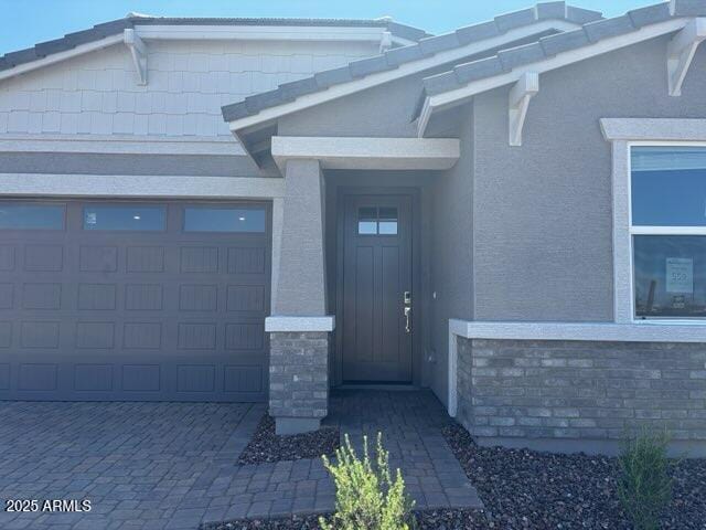 5573 S 246th Ave, Buckeye, AZ 85326 - property entrance with stone siding, a garage, stucco siding, and driveway