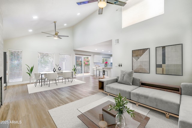 living room with ceiling fan, high vaulted ceiling, and light hardwood / wood-style floors