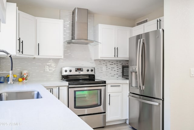 kitchen with white cabinetry, appliances with stainless steel finishes, and wall chimney range hood