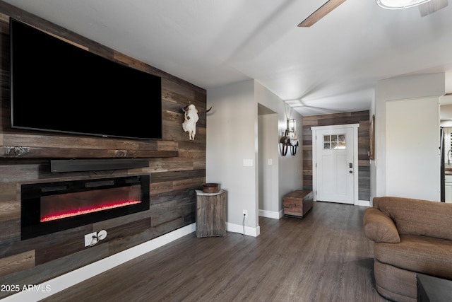 living room with ceiling fan, wooden walls, and dark hardwood / wood-style flooring