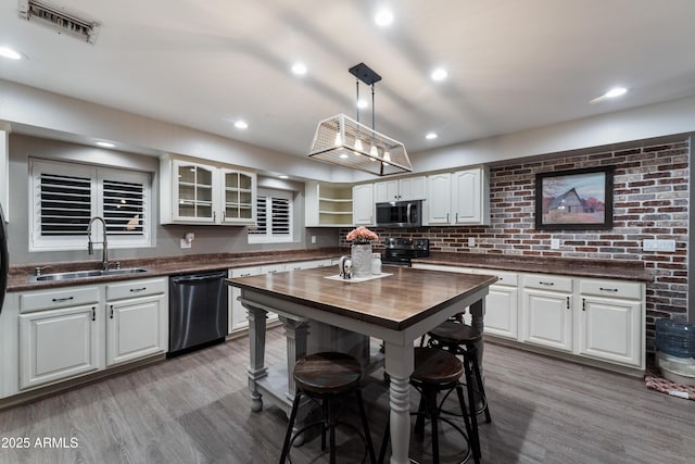 kitchen with light hardwood / wood-style flooring, hanging light fixtures, sink, white cabinets, and stainless steel appliances