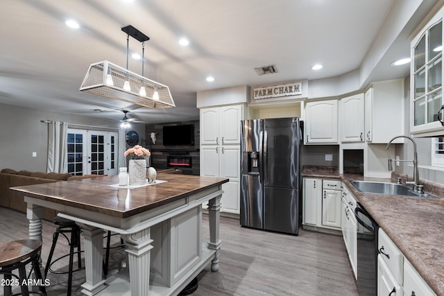 kitchen featuring pendant lighting, sink, white cabinets, a fireplace, and black appliances