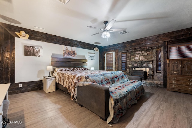 bedroom featuring wood walls, light hardwood / wood-style floors, beamed ceiling, and ceiling fan