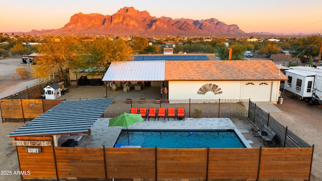 pool at dusk featuring a mountain view and a patio area