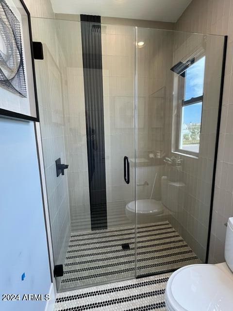 bathroom with tile walls, a shower with door, and toilet