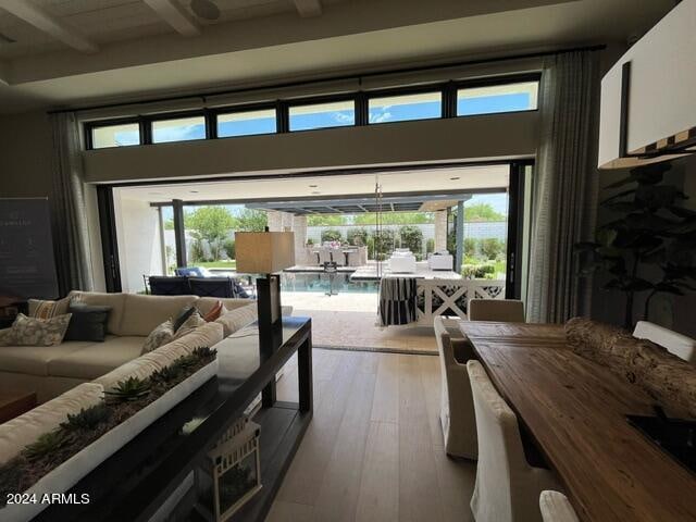 living room with a wealth of natural light, hardwood / wood-style floors, and beam ceiling