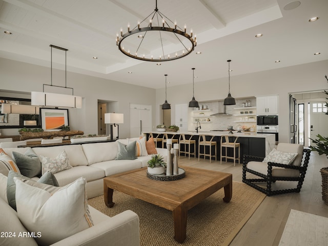 living room featuring a notable chandelier, sink, a raised ceiling, and hardwood / wood-style floors