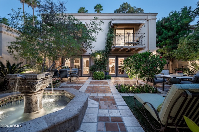 back of property featuring a balcony, a patio, and french doors