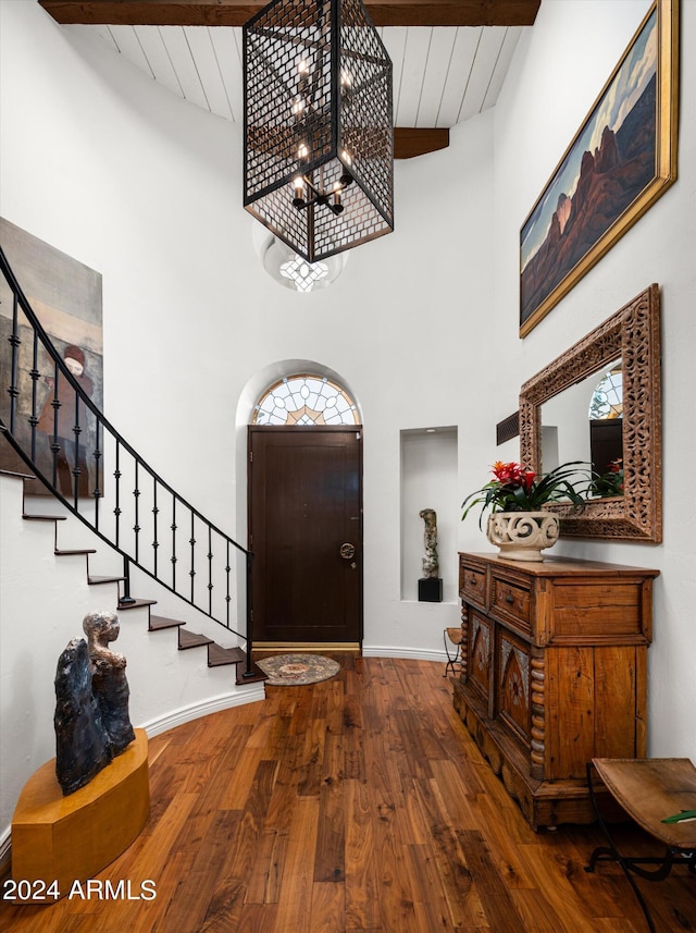 foyer entrance with beam ceiling, hardwood / wood-style floors, wooden ceiling, and a high ceiling