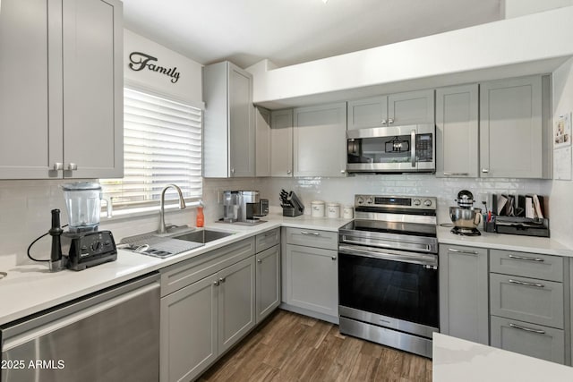 kitchen with gray cabinetry, dark hardwood / wood-style floors, sink, and appliances with stainless steel finishes