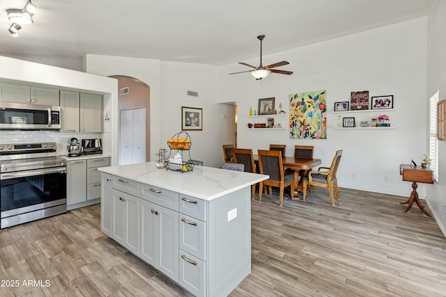 kitchen with a kitchen island, light hardwood / wood-style floors, backsplash, and appliances with stainless steel finishes