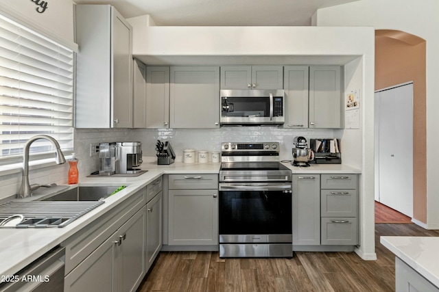 kitchen featuring backsplash, stainless steel appliances, sink, gray cabinets, and dark hardwood / wood-style floors