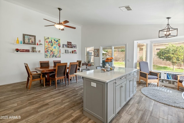 kitchen featuring gray cabinets, a center island, decorative light fixtures, and hardwood / wood-style flooring