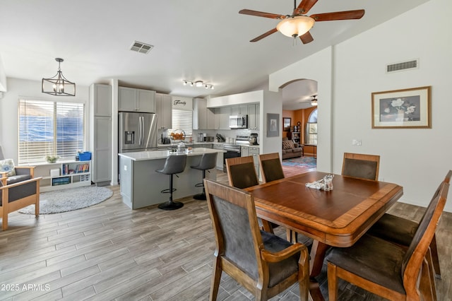 dining room with ceiling fan with notable chandelier, a wealth of natural light, and lofted ceiling