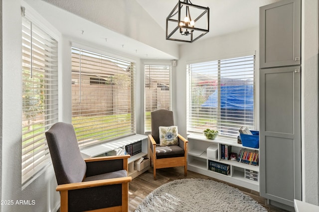 sitting room featuring a healthy amount of sunlight, dark hardwood / wood-style flooring, a chandelier, and lofted ceiling