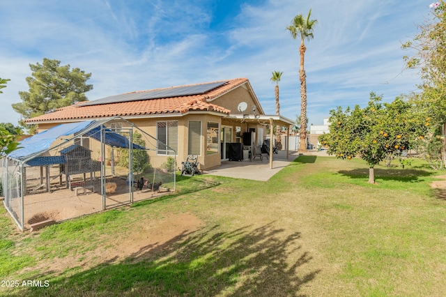 rear view of property featuring a lawn, a patio area, and solar panels