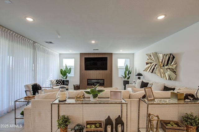 living room featuring a large fireplace, light tile patterned floors, and a wealth of natural light