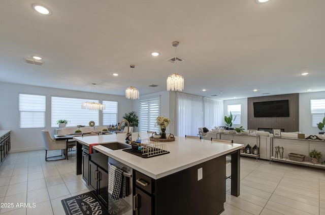 kitchen featuring pendant lighting, light tile patterned floors, a kitchen island with sink, and dishwasher