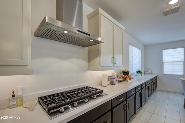 kitchen with white cabinetry, light tile patterned floors, stainless steel gas stovetop, and wall chimney exhaust hood