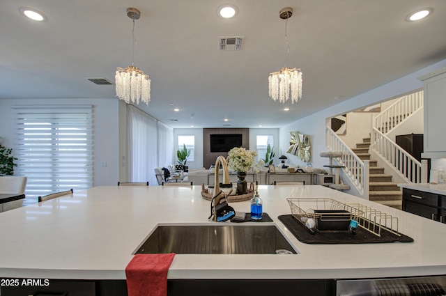 kitchen featuring an island with sink, sink, an inviting chandelier, and decorative light fixtures