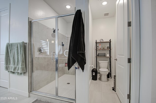 bathroom featuring tile patterned floors, toilet, and a shower with door