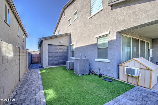 back of house with an outbuilding, a garage, a yard, and cooling unit