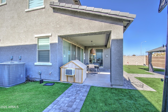 rear view of property with a yard, a patio area, a wall unit AC, and central air condition unit